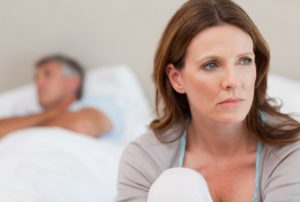 Sad Woman Sitting Next to Her Husband Sleeping on the Bed
