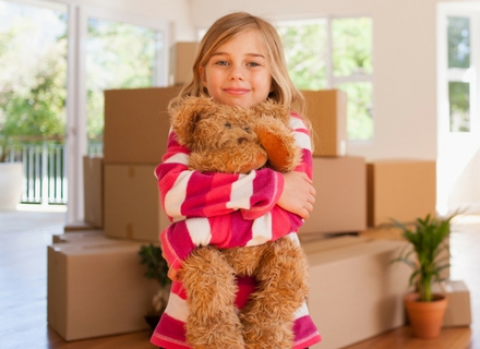 girl-child-holding-teddy-bear-moving-boxes